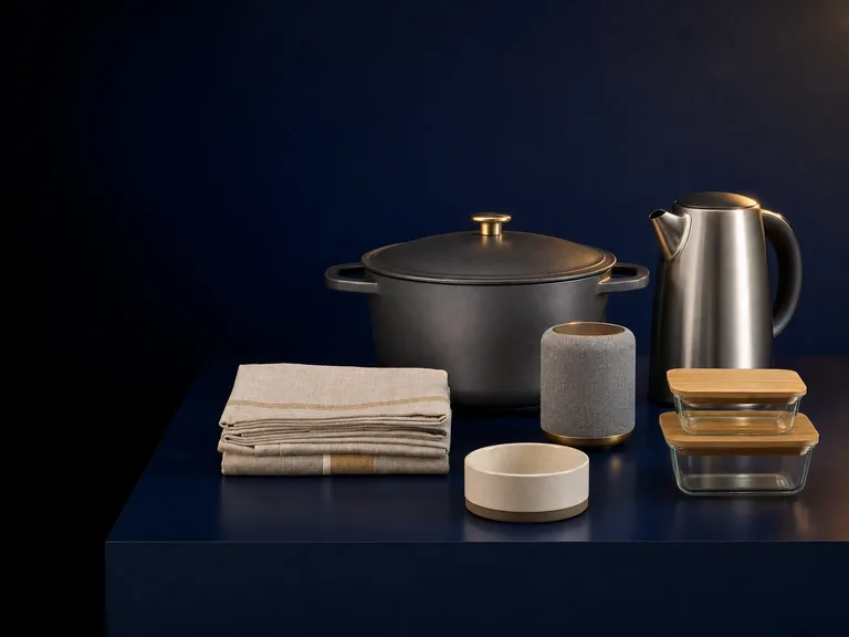 Example lifestyle goods: an enamel casserole pot, a steel kettle, a small speaker, linen tea towels, glass storage containers and a ceramic pet bowl.